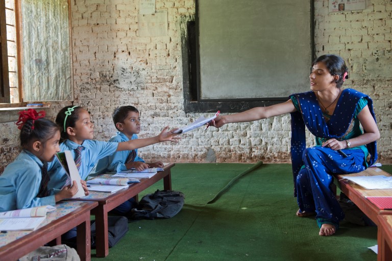 Teacher hands book over to pupil at a Nepali school for the blind