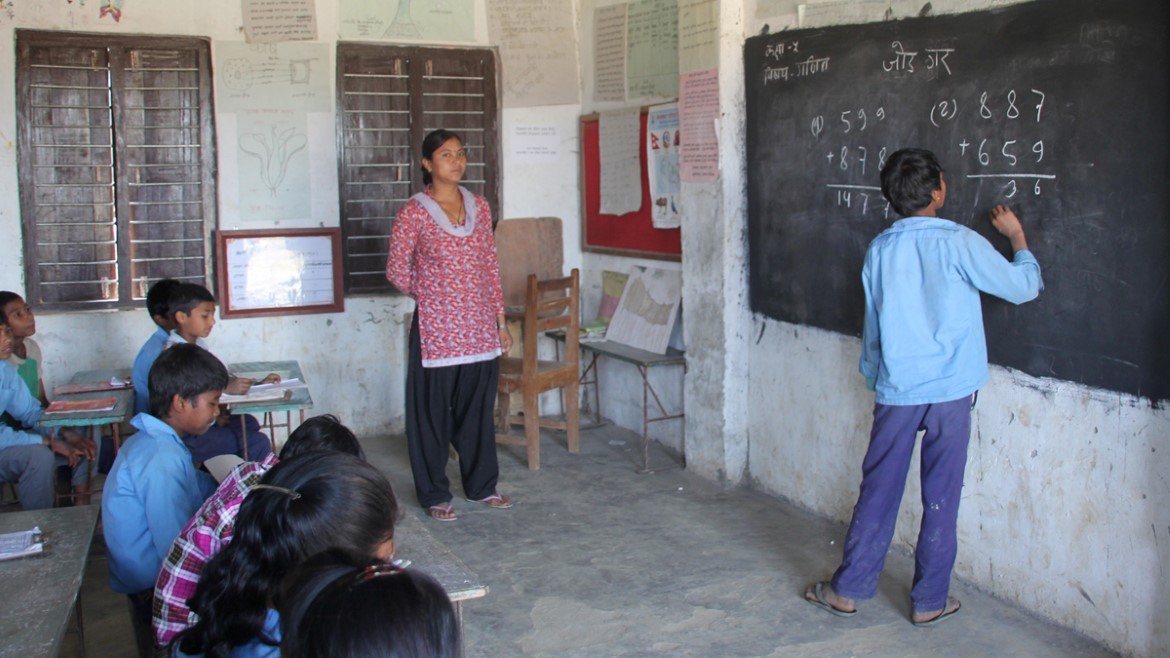 Gutt løser mattestykke oppe på tavla på skole i Nepal