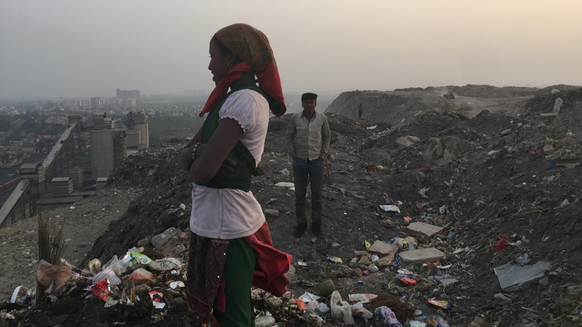 Kvinne står på søppelplassen Okhla landfill i Delhi, hvor restsøppel dumpes
