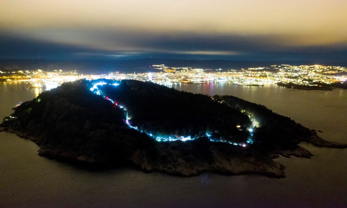 Dronebilde av Odderøya som lyses opp under nattevandring i Kristiansand