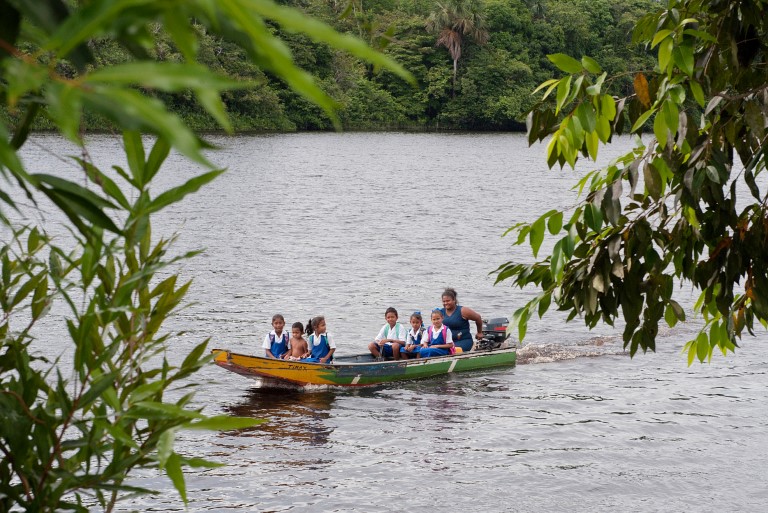 Barn og kvinne i båt i regnskogen i Guyana