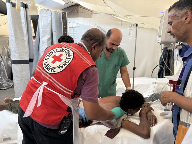 Leger fra Røde Kors behandler en pasient som er et barn i feltsykehuset.