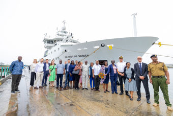 Bildet viser en gruppe mennesker som står på en brygge foran et stort forskningsskip med navnet "Dr. Fridtjof Nansen" malt på skroget. 