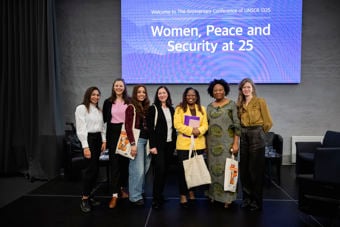 Bildet viser en gruppe kvinner som står sammen foran en blå bakgrunn med teksten "Women, Peace and Security at 25"