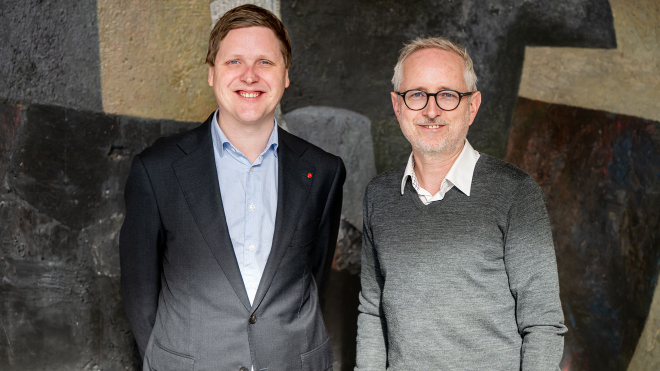 Utviklingsminister Åsmund Grøver Aukrust (til venstre) og avtroppende Norad direktør Bård Vegar Solhjell står ved siden av hverandre og smiler til kameraet.
