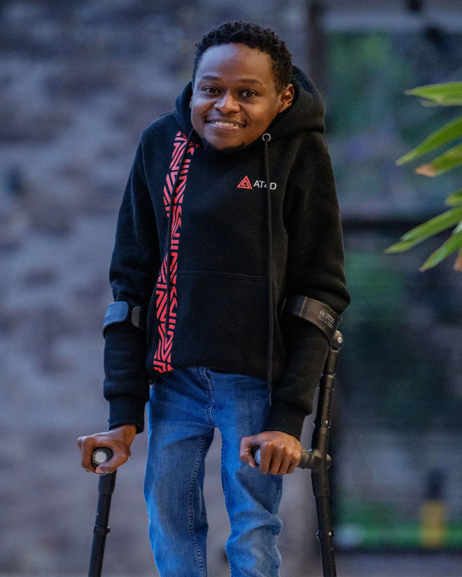 Man with crutches is smiling to the camera.