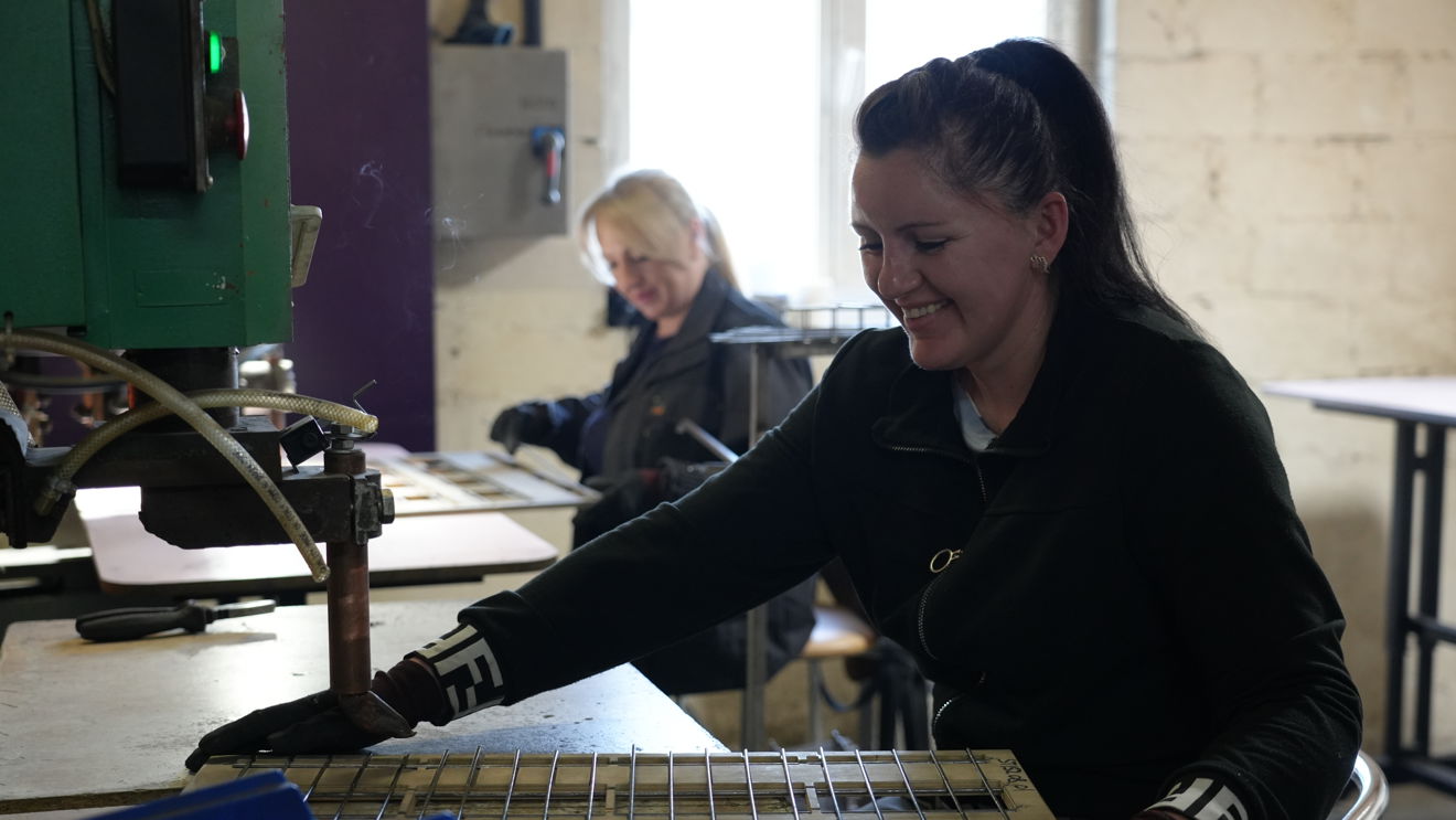 Two female employees weld wire shelves for shop fittings inside the MARKQUEN Company factory.