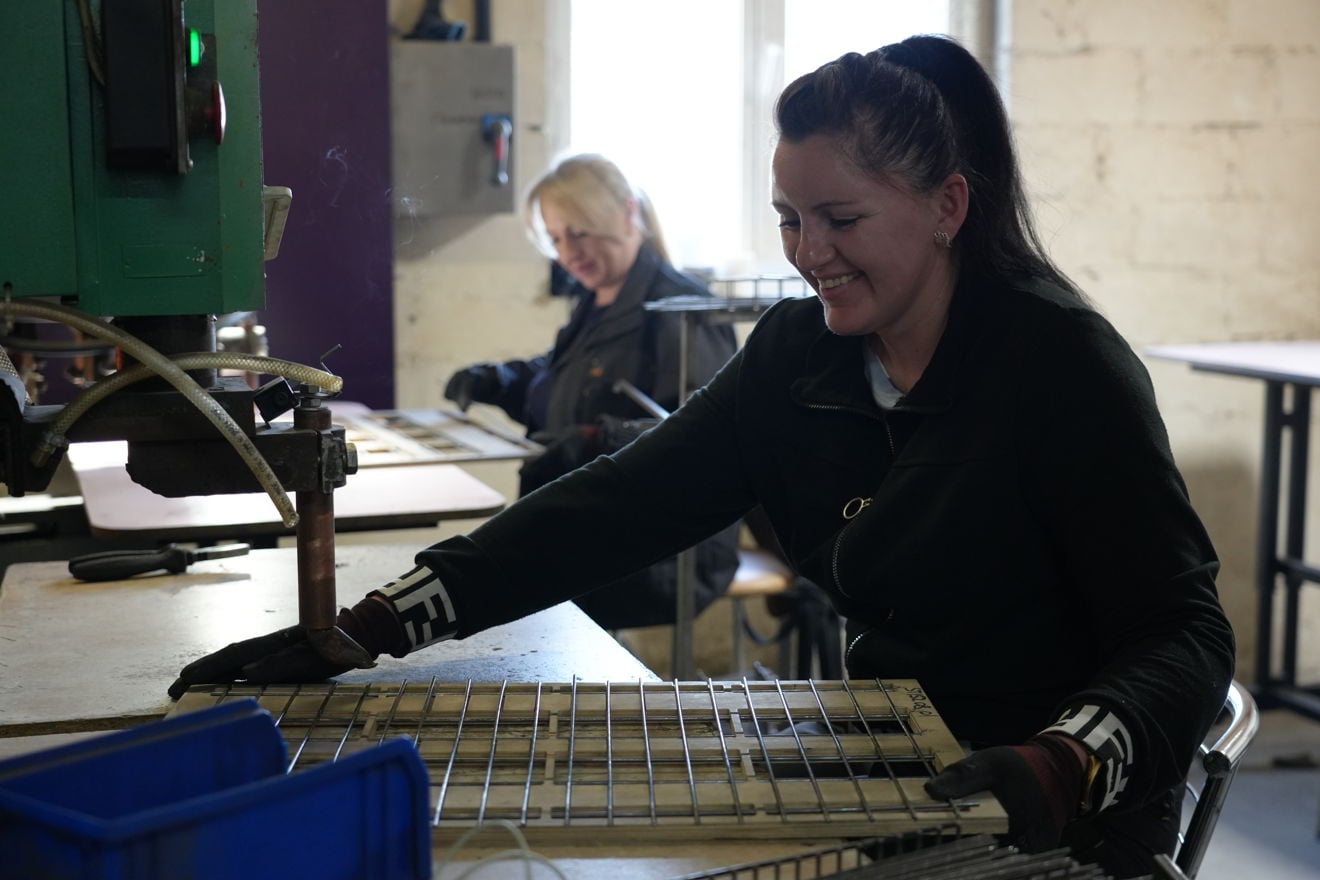 Two female employees weld wire shelves for shop fittings inside the MARKQUEN Company factory.