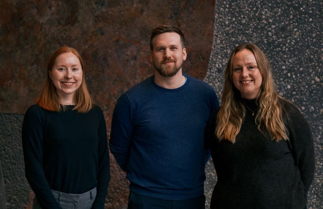 To kvinner og én mann står side om side foran en mørk bakgrunn.