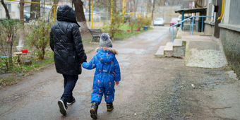 Sett bakfra på en vei: kvinne som holder en liten gutt i hånden. 