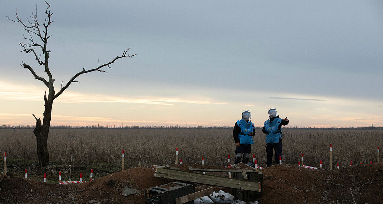 Mine clearance teams in Ukraine are standing in an empty landscape.