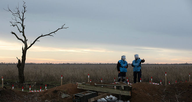 Mine clearance teams in Ukraine are standing in an empty landscape.