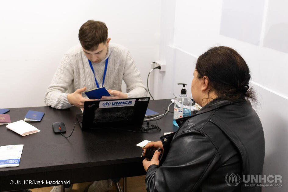 A woman is sitting with her back turned in an office with a man who is working on a computer