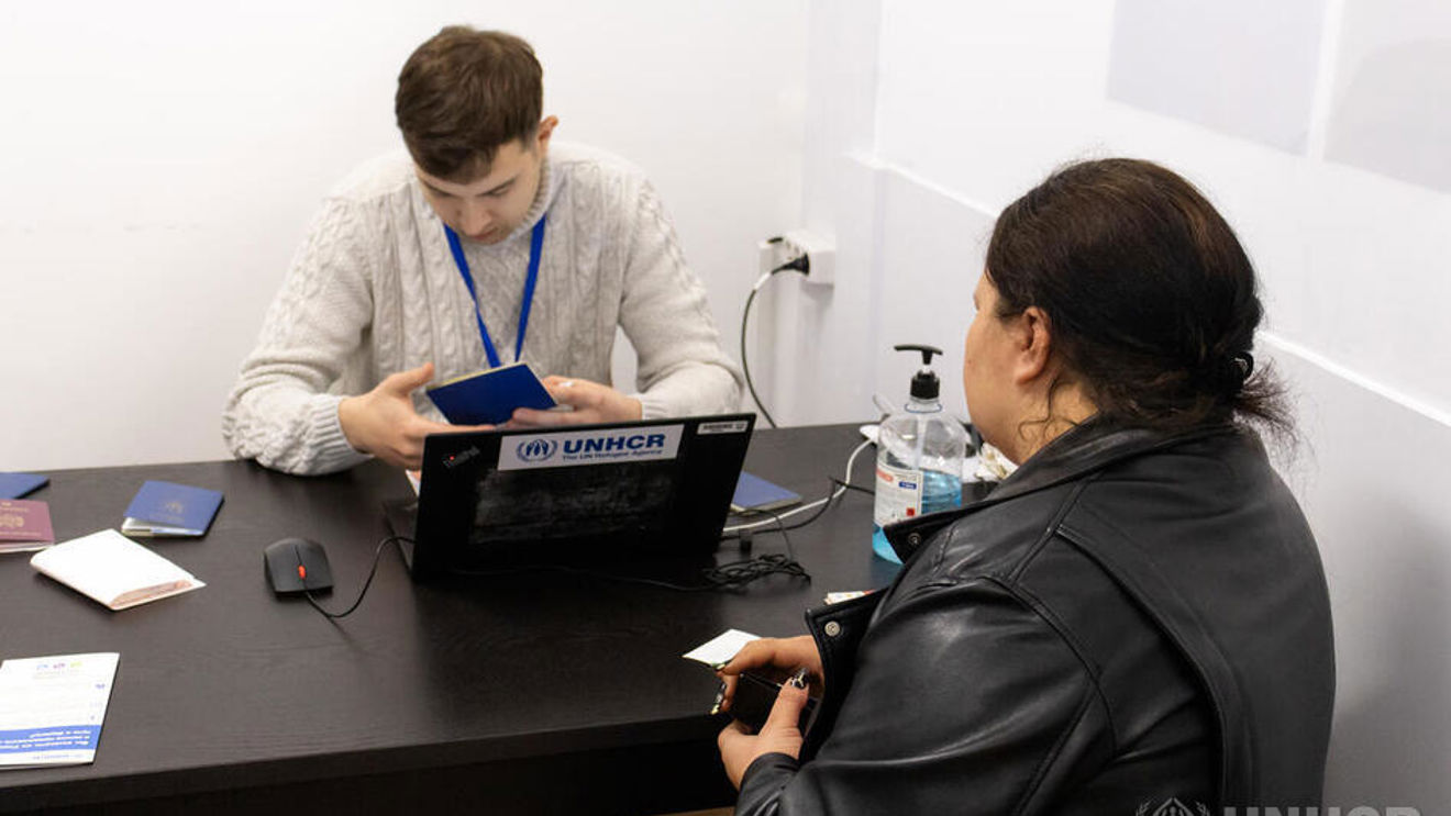 A woman is sitting with her back turned in an office with a man who is working on a computer