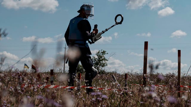 Man with mining tools in his hands stands alone in a dry landscape.