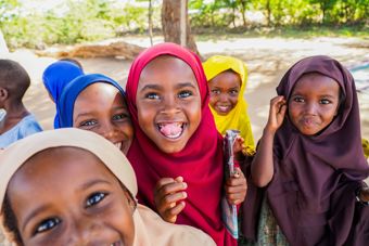  En gruppe unge jenter står sammen utendørs, iført fargerike hodeplagg og klær.